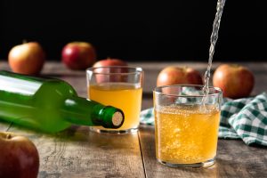 pouring apple cider drink into glass wooden table